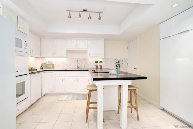 kitchen featuring white cabinets, a tray ceiling, and a breakfast bar area