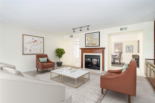 living room featuring rail lighting, a fireplace with flush hearth, visible vents, and baseboards