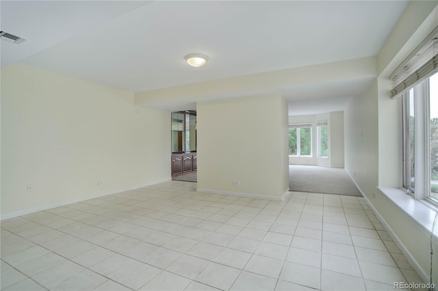 spare room featuring light tile patterned flooring, visible vents, and baseboards