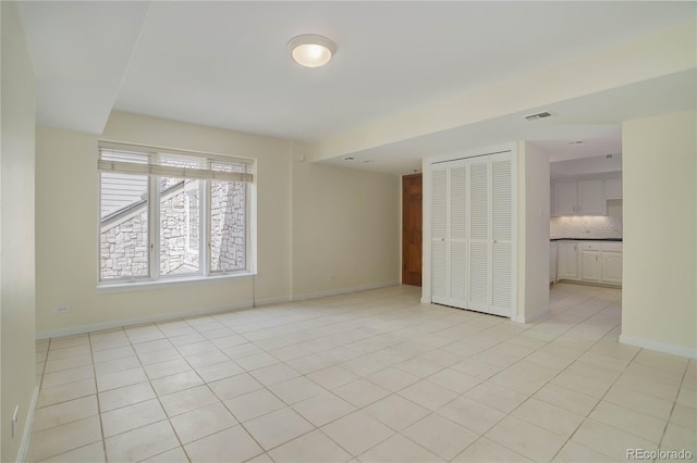 unfurnished bedroom with a closet, visible vents, baseboards, and light tile patterned floors