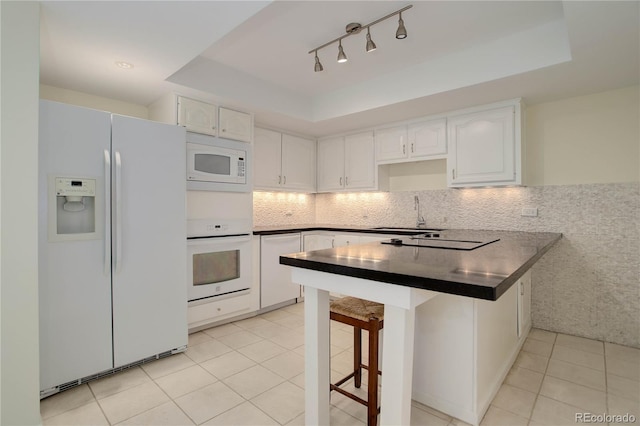 kitchen with dark countertops, white appliances, light tile patterned floors, and white cabinets