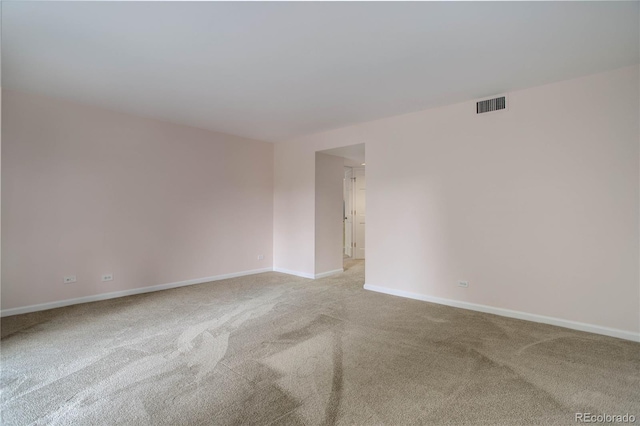 unfurnished room with baseboards, visible vents, and light colored carpet