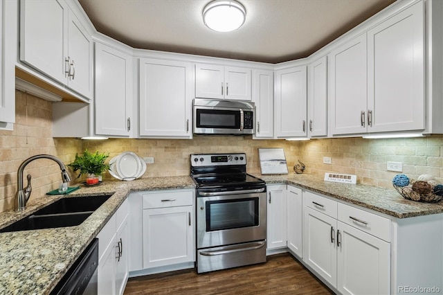 kitchen featuring appliances with stainless steel finishes, white cabinetry, sink, backsplash, and light stone counters