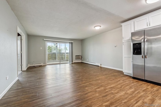 interior space with a wall mounted air conditioner, a baseboard radiator, hardwood / wood-style flooring, and a textured ceiling