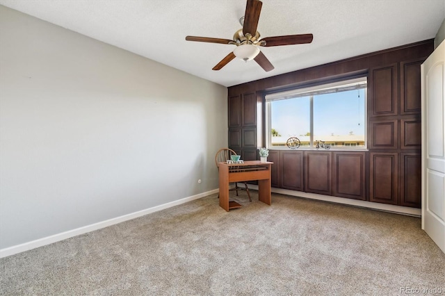 carpeted office space featuring ceiling fan