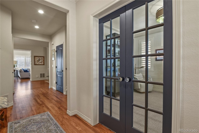 interior space with french doors, visible vents, baseboards, and wood finished floors