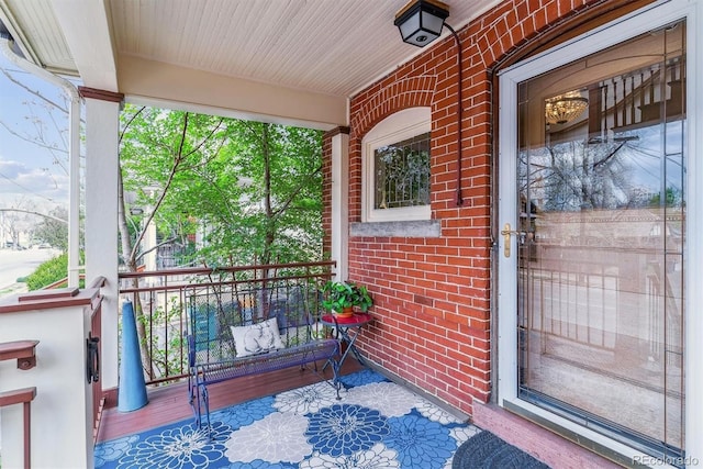 view of exterior entry featuring a porch and brick siding