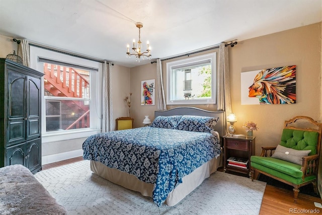 bedroom with baseboards, a chandelier, and light wood finished floors