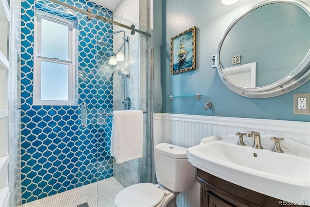 bathroom with a tile shower, wainscoting, a sink, and a healthy amount of sunlight