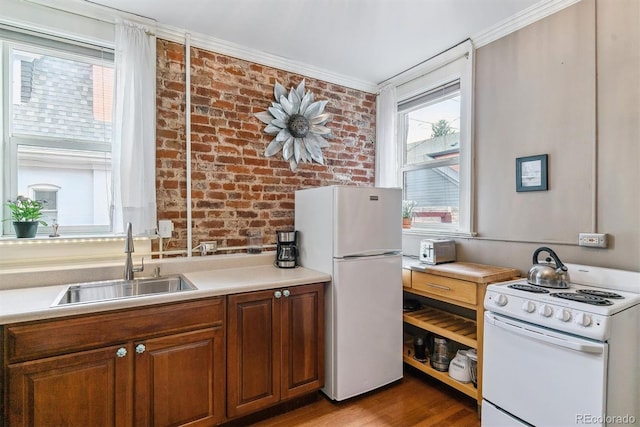 kitchen featuring a sink, white appliances, light countertops, brick wall, and ornamental molding