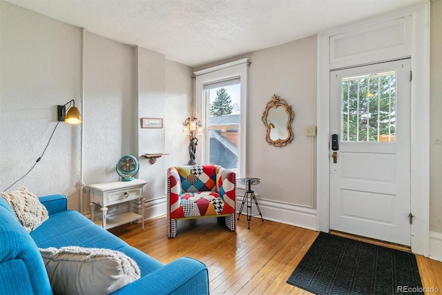 sitting room with baseboards, a textured ceiling, and light wood-style flooring