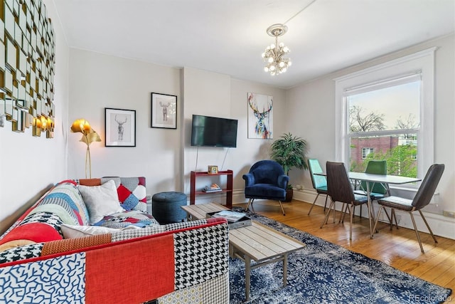 living area with baseboards, wood finished floors, and a chandelier