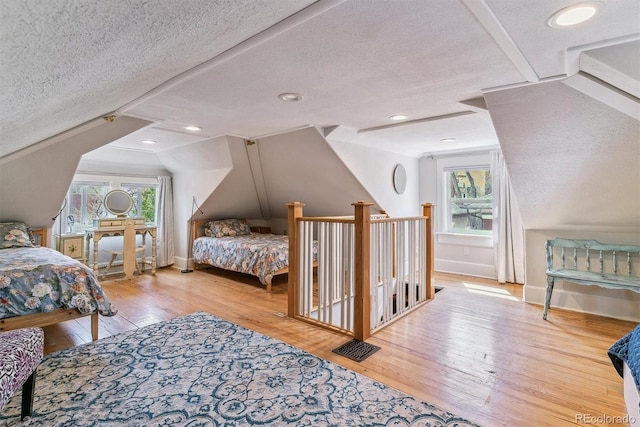 bedroom featuring wood-type flooring, a textured ceiling, baseboards, and lofted ceiling