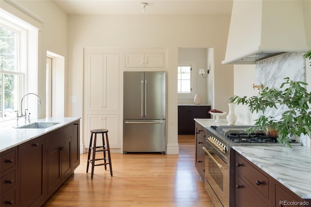 3330 Bruce Randolph Ave, Denver, CO 80205 - kitchen with premium appliances, a sink, premium range hood, light wood-type flooring, and dark brown cabinetry