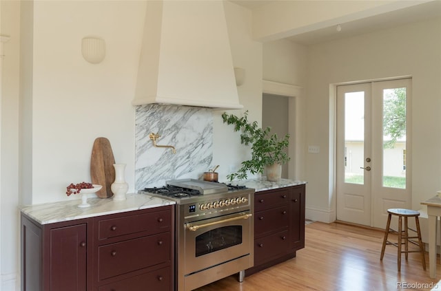 3330 Bruce Randolph Ave, Denver, CO 80205 - kitchen with high end range, tasteful backsplash, french doors, light wood finished floors, and custom range hood