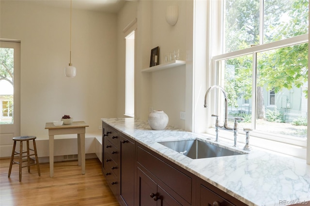 3330 Bruce Randolph Ave, Denver, CO 80205 - kitchen featuring a sink, light wood-style flooring, light stone counters, dark brown cabinets, and pendant lighting