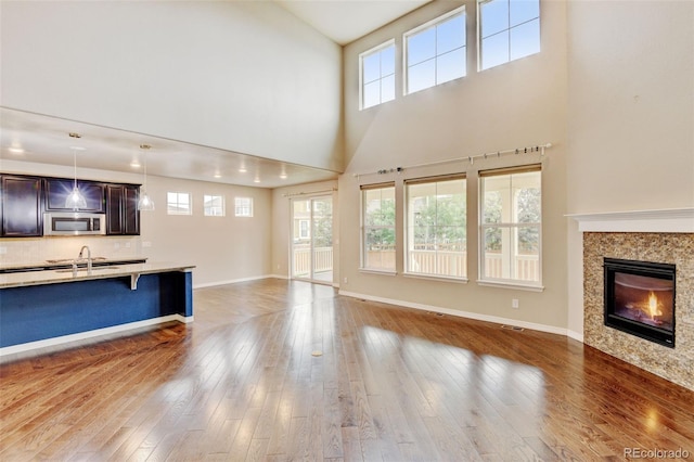 2454 Ambience Ln, Castle Rock, CO 80109 - unfurnished living room featuring a sink, a high ceiling, plenty of natural light, hardwood / wood-style flooring, and baseboards