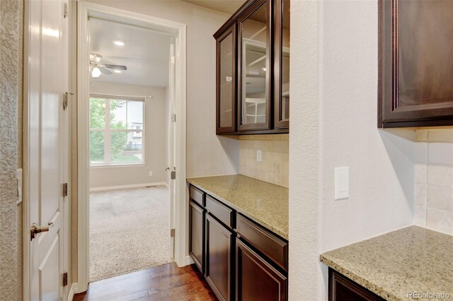 2454 Ambience Ln, Castle Rock, CO 80109 - kitchen with decorative backsplash, dark brown cabinetry, glass insert cabinets, and ceiling fan