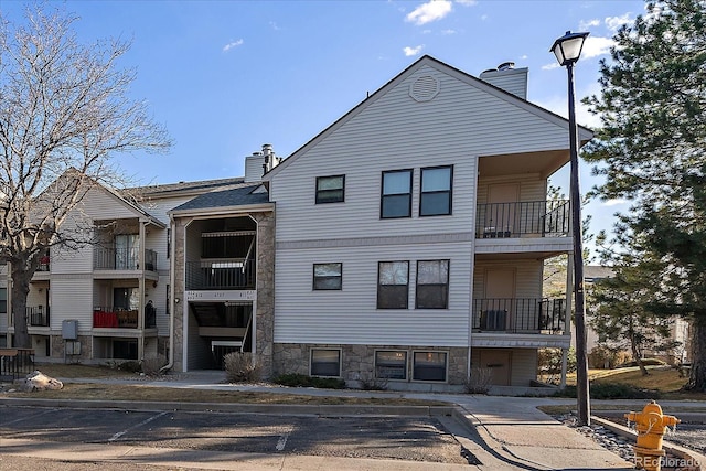 view of building exterior with central AC unit and uncovered parking