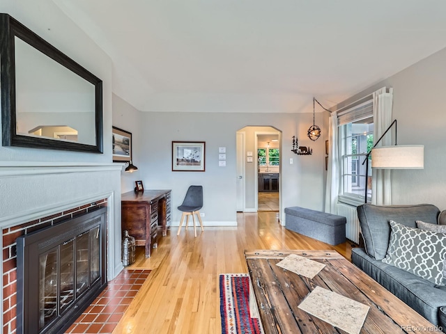 2626 N Steele St, Denver, CO 80205 - living room featuring arched walkways, wood finished floors, a fireplace with flush hearth, and radiator