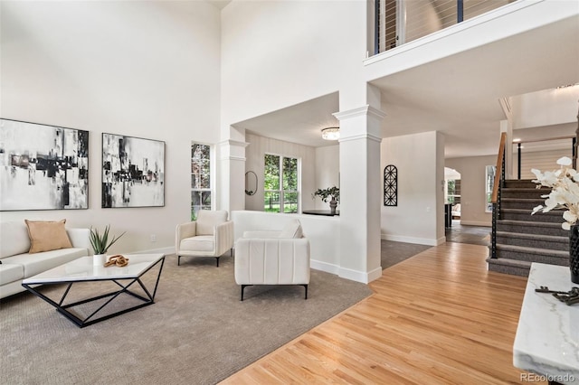 2037 River W Dr, Windsor, CO 80550 - living room featuring ornate columns, wood finished floors, stairs, and a towering ceiling
