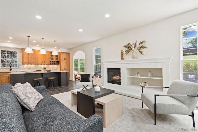 2037 River W Dr, Windsor, CO 80550 - living room with recessed lighting, a brick fireplace, arched walkways, light tile patterned floors, and built in features