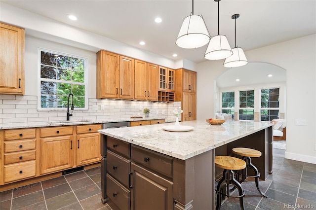 2037 River W Dr, Windsor, CO 80550 - kitchen with a breakfast bar area, backsplash, a center island, light stone counters, and recessed lighting