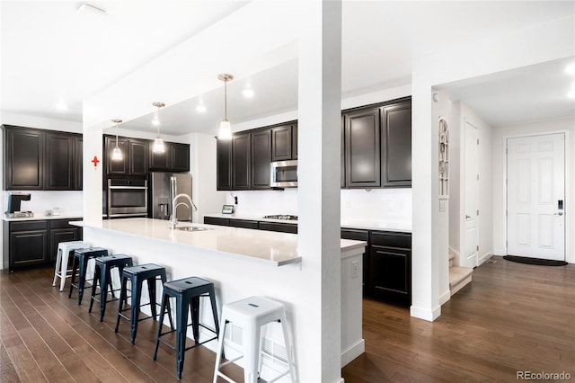 14454 Grape Way, Thornton, CO 80602 - kitchen with appliances with stainless steel finishes, a sink, dark wood-style flooring, a spacious island, and recessed lighting