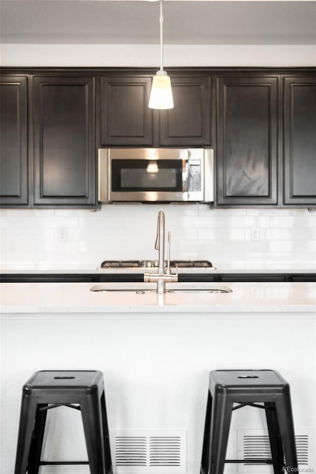 14454 Grape Way, Thornton, CO 80602 - kitchen with stainless steel microwave, decorative backsplash, dark brown cabinets, and a sink