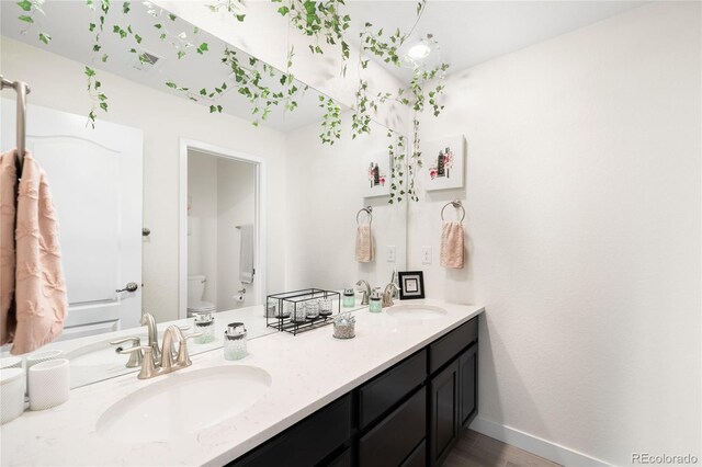 14454 Grape Way, Thornton, CO 80602 - bathroom with toilet, double vanity, baseboards, and wood finished floors