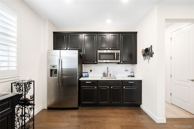 14454 Grape Way, Thornton, CO 80602 - kitchen with stainless steel appliances, a sink, wood finished floors, light countertops, and backsplash