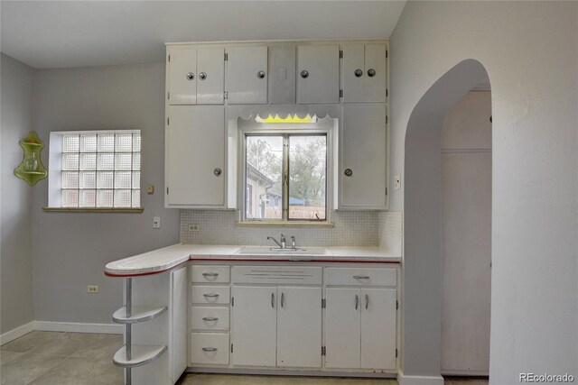 4514 Bryant St, Denver, CO 80211 - kitchen with tile counters, white cabinets, decorative backsplash, and arched walkways