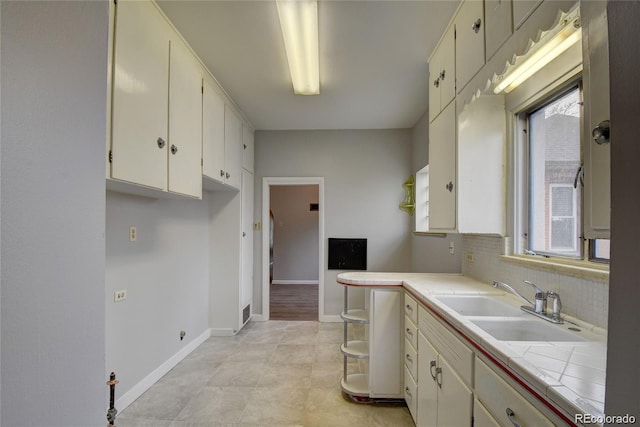 4514 Bryant St, Denver, CO 80211 - kitchen featuring a sink, backsplash, white cabinetry, baseboards, and tile counters