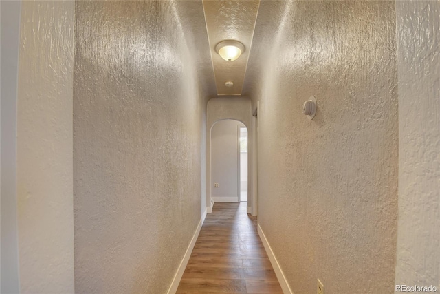 4514 Bryant St, Denver, CO 80211 - hall featuring a textured wall, wood finished floors, arched walkways, and baseboards