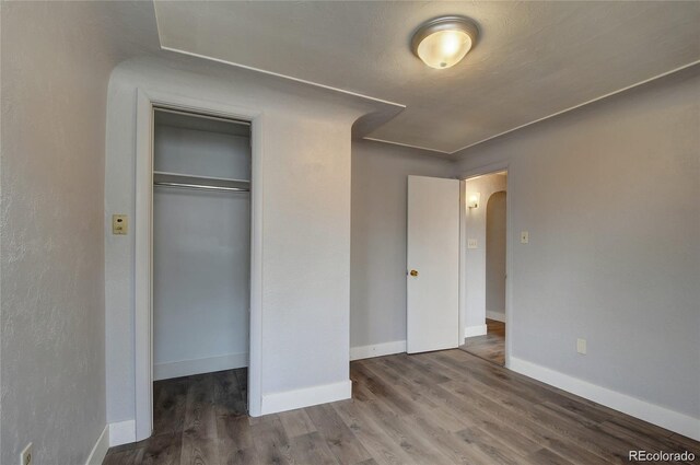 4514 Bryant St, Denver, CO 80211 - unfurnished bedroom with arched walkways, a closet, wood finished floors, and baseboards