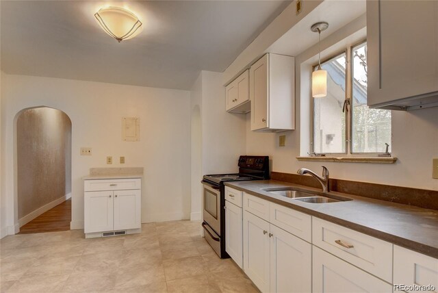 4514 Bryant St, Denver, CO 80211 - kitchen with electric range, arched walkways, a sink, white cabinetry, and hanging light fixtures