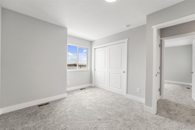 unfurnished bedroom featuring light carpet and a closet