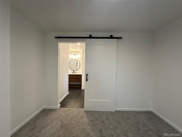 empty room featuring dark carpet and a barn door