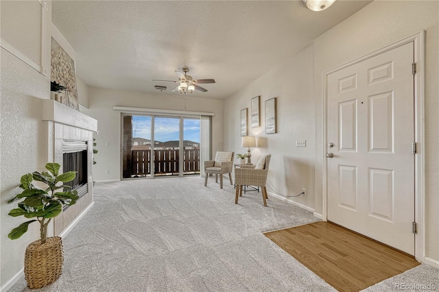 living area featuring ceiling fan, light carpet, and a textured ceiling