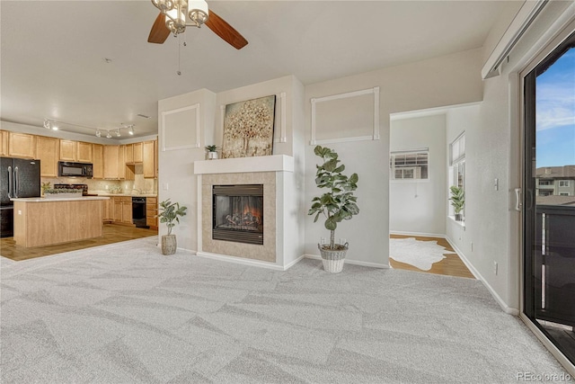 carpeted living room with a tiled fireplace, rail lighting, and ceiling fan