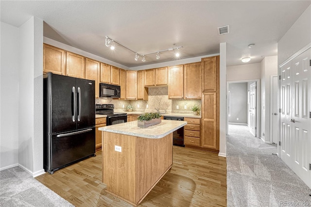 kitchen featuring tasteful backsplash, light hardwood / wood-style flooring, black appliances, and a kitchen island