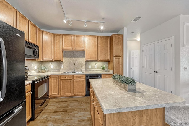 kitchen with sink, tasteful backsplash, a center island, light wood-type flooring, and black appliances