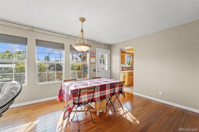 dining space with hardwood / wood-style floors and a textured ceiling