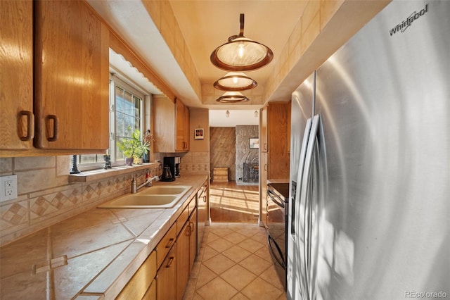 kitchen with tile counters, sink, stainless steel appliances, tasteful backsplash, and light tile patterned floors