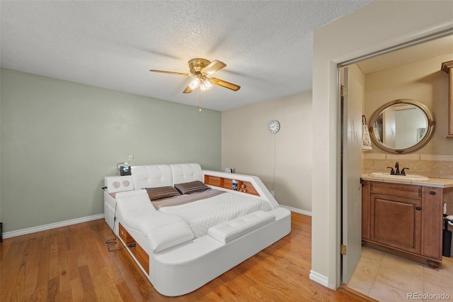 bedroom featuring a textured ceiling, ceiling fan, sink, and light hardwood / wood-style flooring