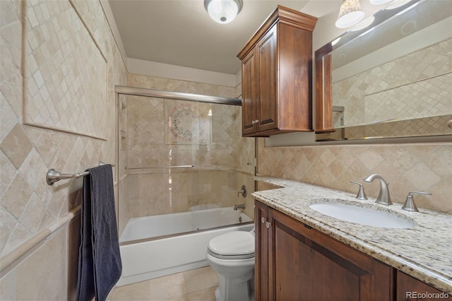 full bathroom featuring tasteful backsplash, tile patterned flooring, bath / shower combo with glass door, toilet, and vanity