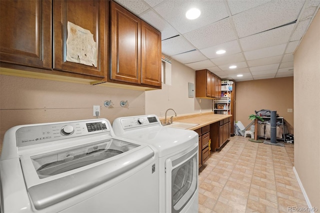 clothes washing area with washer and dryer, cabinets, and sink