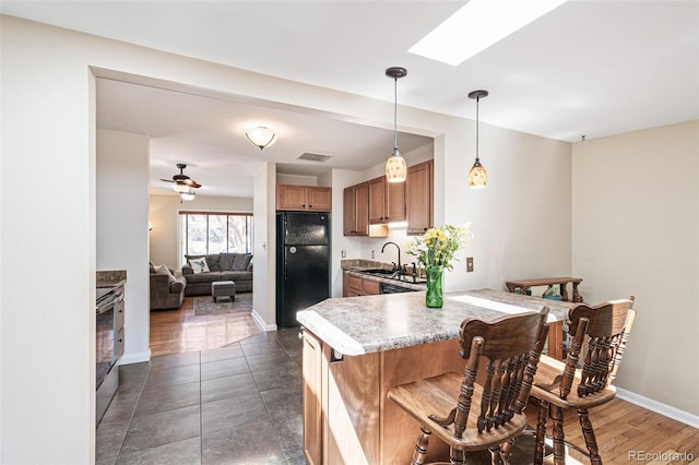 2252 Lamar St, Edgewater, CO 80214 - kitchen with freestanding refrigerator, a peninsula, a sink, brown cabinets, and light countertops