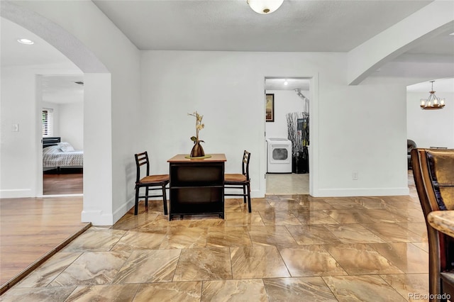 interior space featuring a textured ceiling, washer / dryer, a chandelier, and light hardwood / wood-style floors