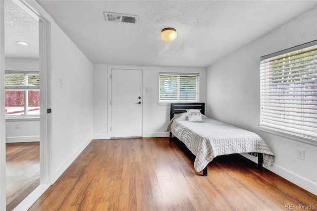 bedroom with a textured ceiling and wood-type flooring